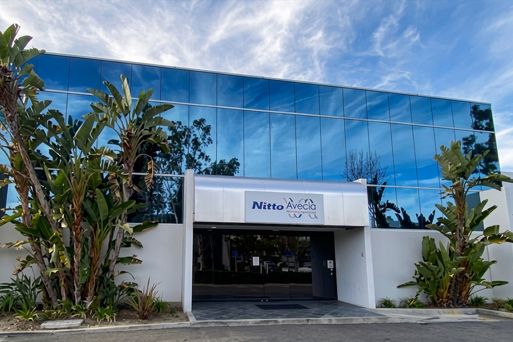 Exterior entrance of the Nitto Avecia facility with glass facade and palm trees